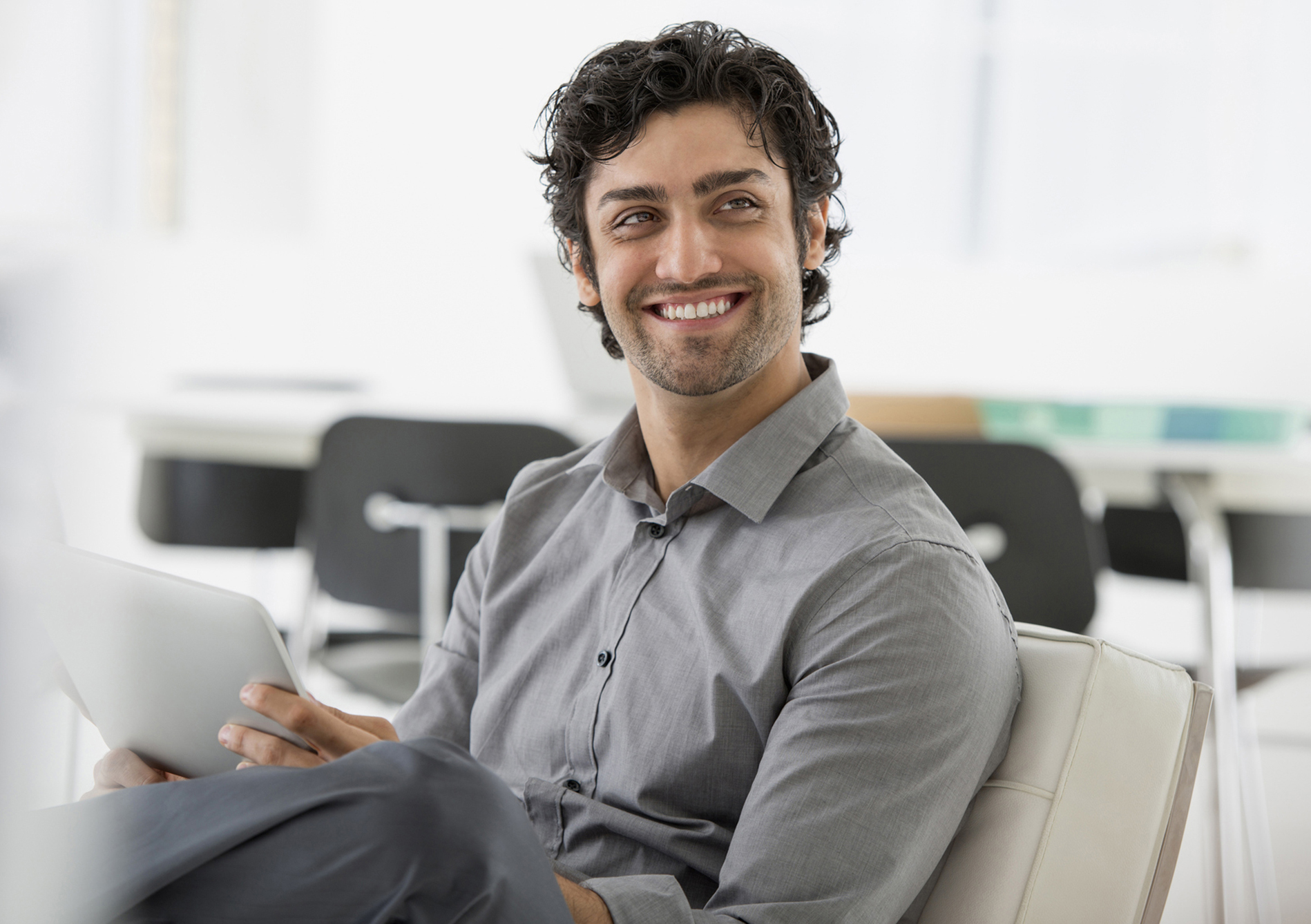 A man with curly hair holding a tablet computer.