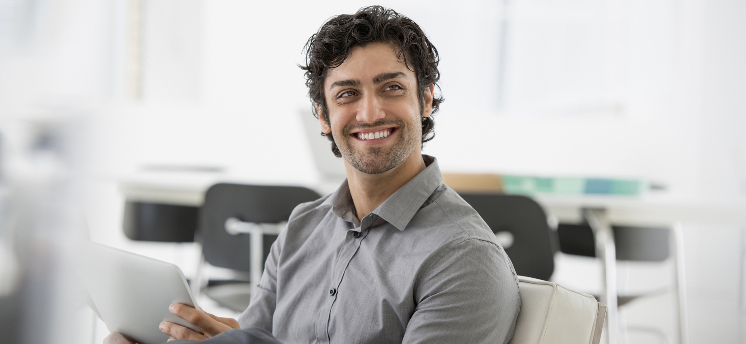 A man with curly hair holding a tablet computer.