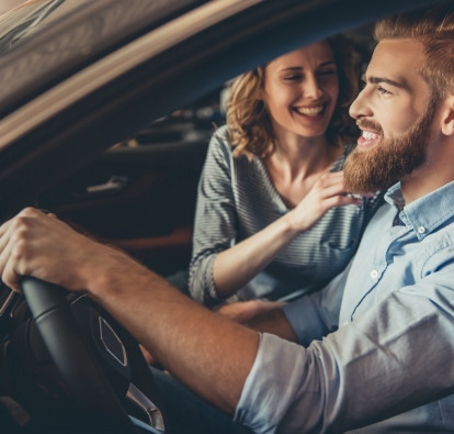 A man and a woman smiling while sitting in a car.