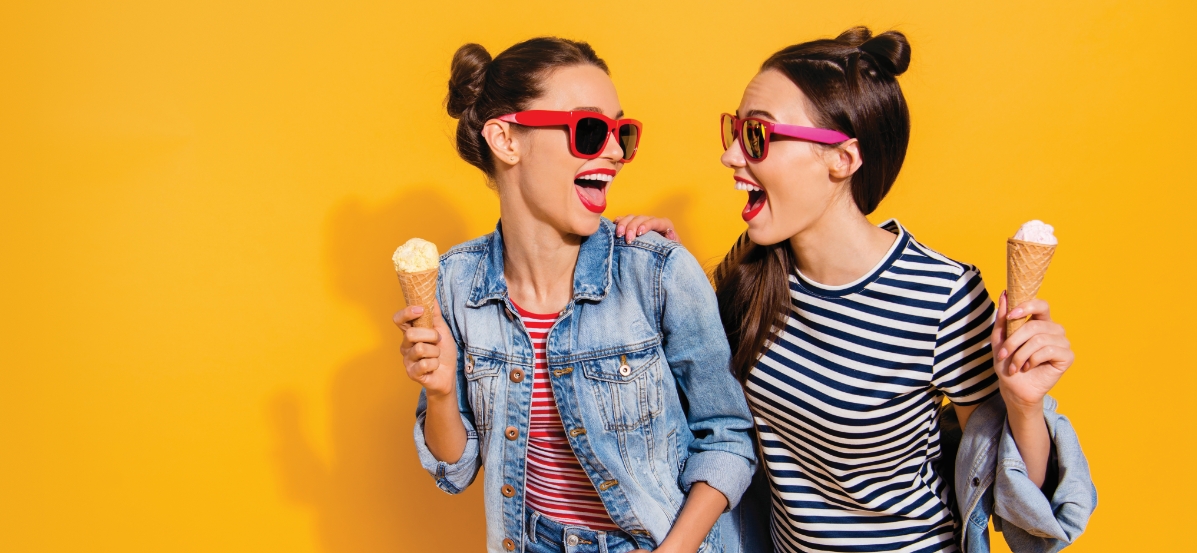 Two girls in sunglasses laughing.