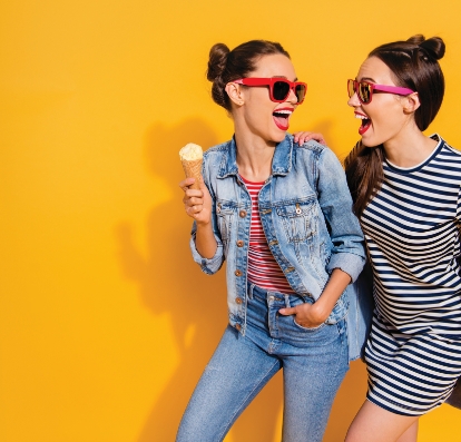 Two girls in sunglasses laughing.