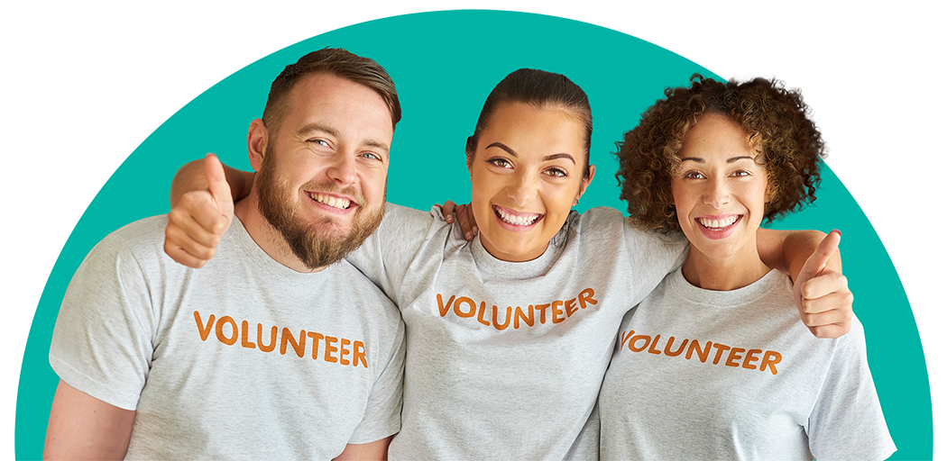 Three smiling volunteers in gray shirts showing nonprofit team spirit and community service.